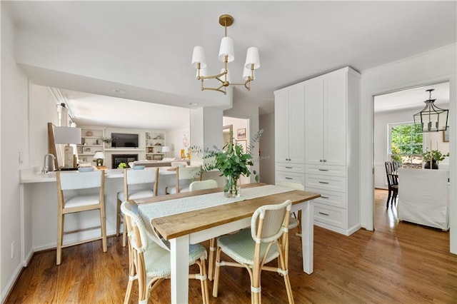 6960 Hunters Branch Dr, Atlanta, GA 30328 - dining area featuring a chandelier, light wood finished floors, and a fireplace