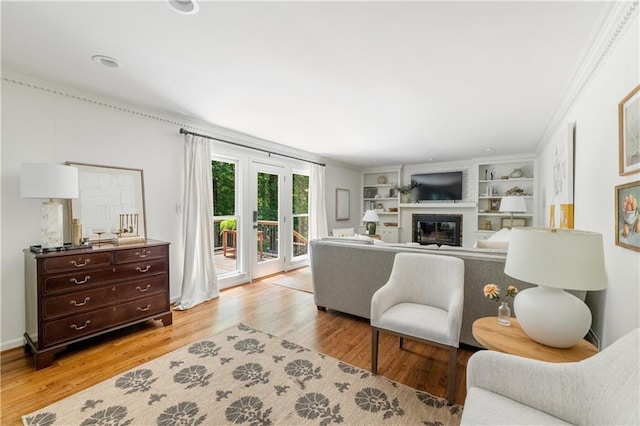 6960 Hunters Branch Dr, Atlanta, GA 30328 - living area with a glass covered fireplace, light wood-style floors, crown molding, and built in shelves