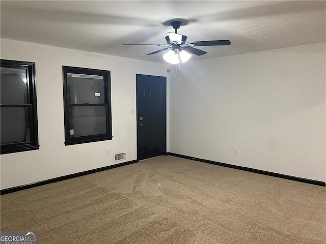 empty room with carpet flooring, visible vents, baseboards, and ceiling fan