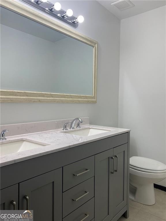 bathroom featuring double vanity, toilet, visible vents, and a sink