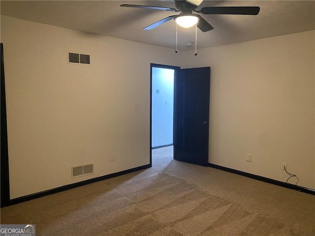 carpeted spare room featuring baseboards, visible vents, and ceiling fan