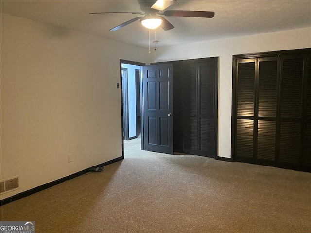 unfurnished bedroom featuring visible vents, two closets, ceiling fan, baseboards, and carpet floors