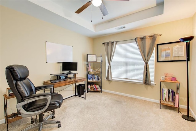 office area featuring ceiling fan, light carpet, and a tray ceiling