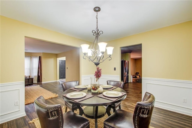 dining room with dark wood-type flooring and an inviting chandelier