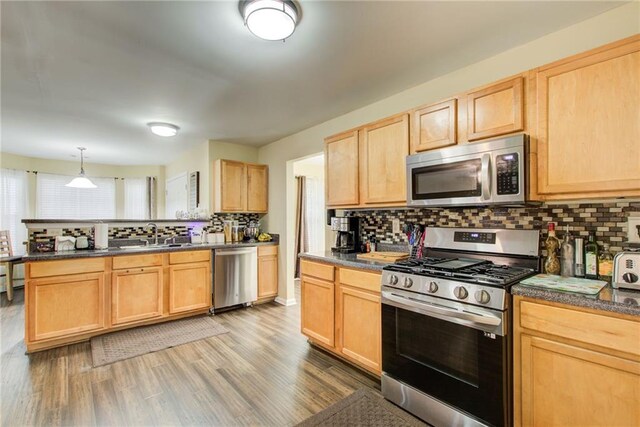 kitchen with appliances with stainless steel finishes, light wood-type flooring, backsplash, sink, and light brown cabinets