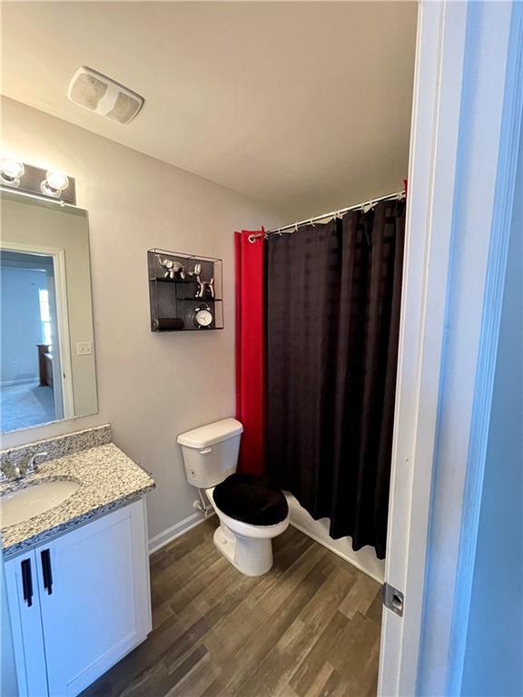 bathroom featuring a shower with curtain, vanity, hardwood / wood-style floors, and toilet