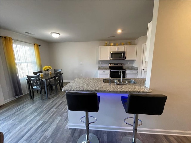 kitchen featuring sink, white cabinets, a kitchen breakfast bar, kitchen peninsula, and electric stove