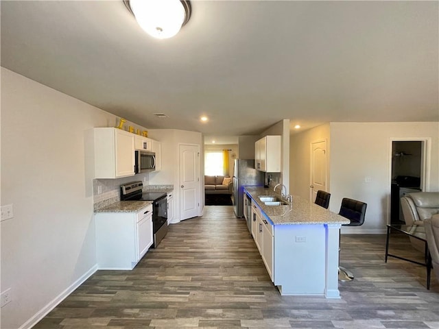 kitchen with a breakfast bar, sink, white cabinets, kitchen peninsula, and stainless steel appliances