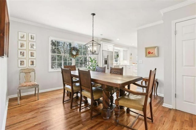 dining space with a notable chandelier, ornamental molding, and light wood-type flooring