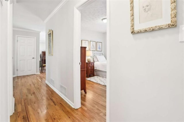 hallway featuring ornamental molding and light wood-type flooring