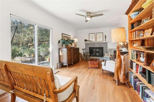 sitting room featuring ceiling fan, light wood-type flooring, and a fireplace