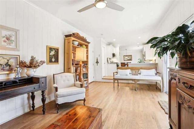 sitting room featuring ceiling fan, ornamental molding, and light wood-type flooring