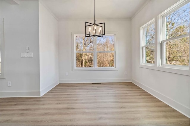 unfurnished dining area featuring a chandelier, crown molding, and light hardwood / wood-style floors