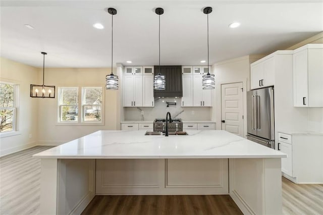 kitchen with white cabinetry, light stone counters, a large island, and high end fridge