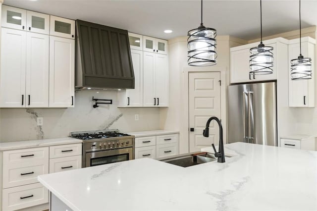 kitchen featuring custom exhaust hood, white cabinetry, sink, hanging light fixtures, and high quality appliances