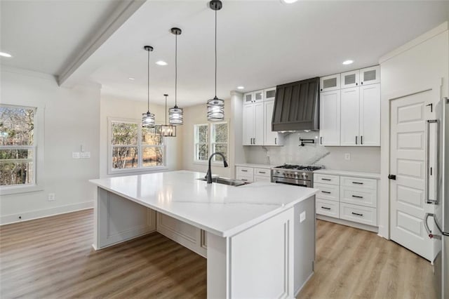 kitchen with premium range hood, white cabinetry, an island with sink, high end appliances, and sink