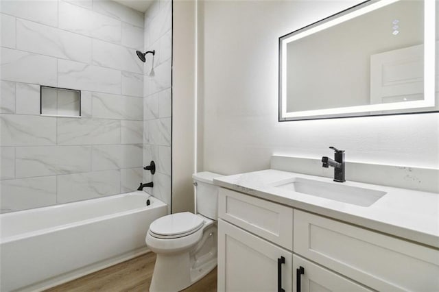 full bathroom featuring toilet, tiled shower / bath combo, wood-type flooring, and vanity