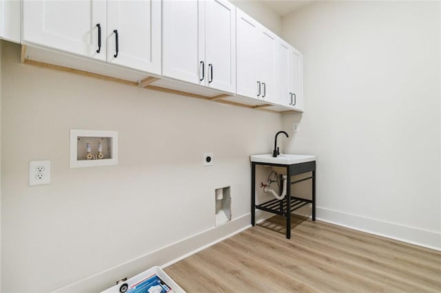 laundry area featuring electric dryer hookup, light wood-type flooring, washer hookup, cabinets, and sink