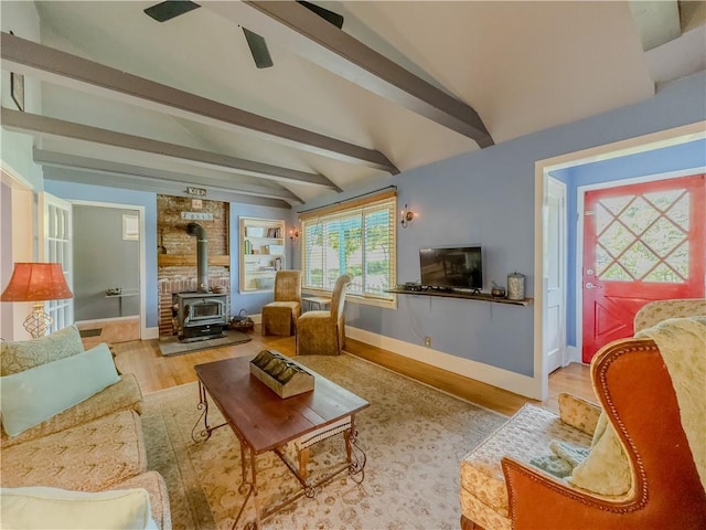 5130 Dearing St, Covington, GA 30014 - living room featuring a wood stove, beamed ceiling, wood finished floors, and a ceiling fan