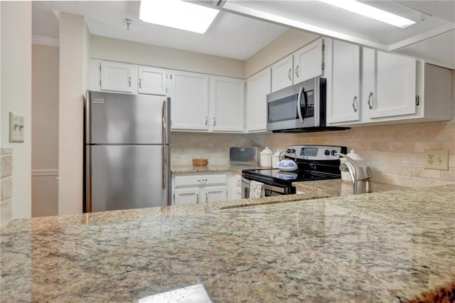 kitchen featuring white cabinetry, tasteful backsplash, appliances with stainless steel finishes, and light stone counters