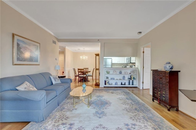 living room featuring a notable chandelier, wood-type flooring, and ornamental molding