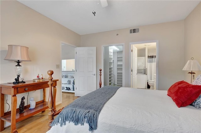 bedroom featuring ceiling fan, ensuite bathroom, wood-type flooring, a walk in closet, and a closet