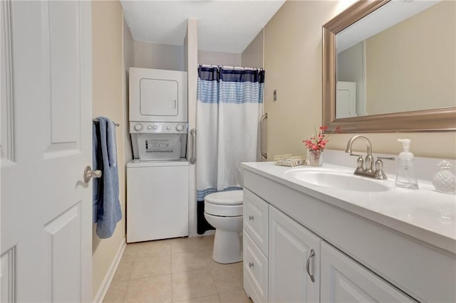 bathroom featuring a shower with shower curtain, vanity, stacked washer / dryer, tile patterned floors, and toilet