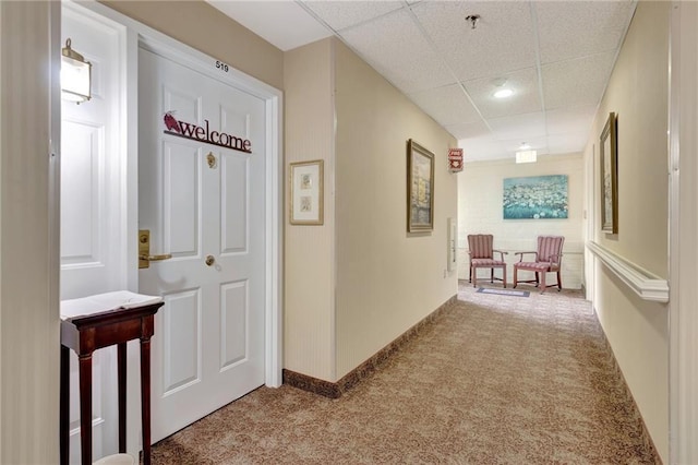 corridor with a drop ceiling and light colored carpet