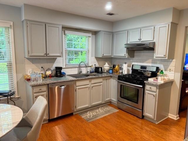 3545 Manchester Dr, Lawrenceville, GA 30044 - kitchen featuring stainless steel appliances, under cabinet range hood, tasteful backsplash, and light wood-style floors