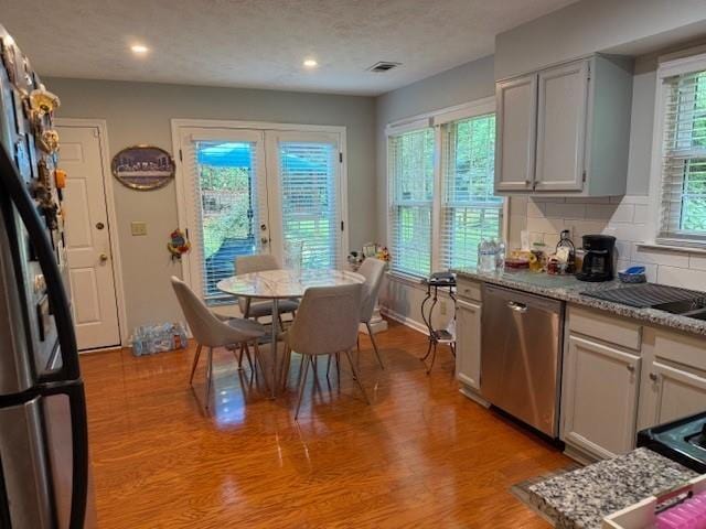 3545 Manchester Dr, Lawrenceville, GA 30044 - kitchen with stainless steel dishwasher, light wood finished floors, freestanding refrigerator, tasteful backsplash, and recessed lighting
