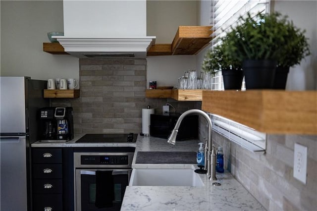 kitchen featuring exhaust hood, decorative backsplash, sink, and stainless steel appliances