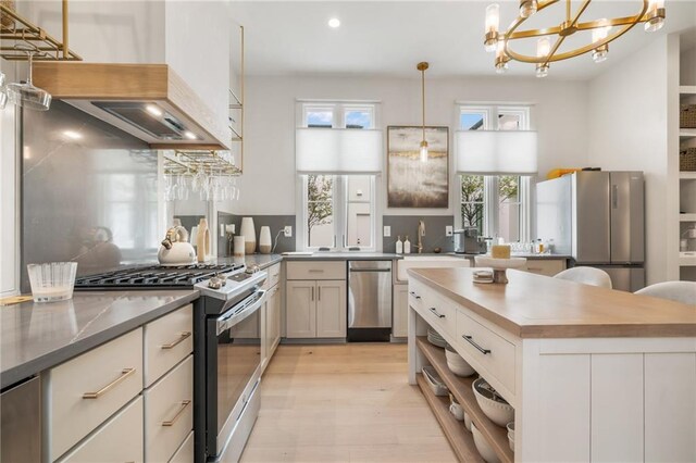 kitchen featuring pendant lighting, sink, wine cooler, light wood-type flooring, and stainless steel appliances