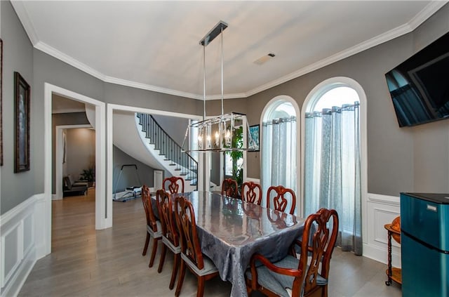 dining room with crown molding, a chandelier, and hardwood / wood-style floors