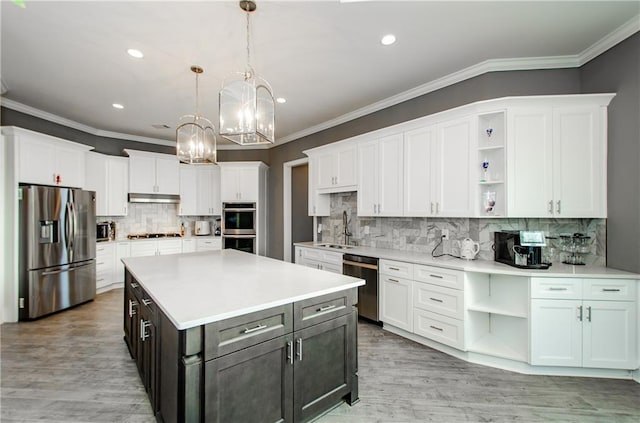 kitchen with crown molding, hanging light fixtures, appliances with stainless steel finishes, a kitchen island, and white cabinets