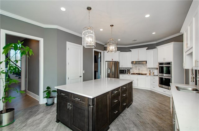 kitchen with sink, a center island, hanging light fixtures, stainless steel appliances, and backsplash