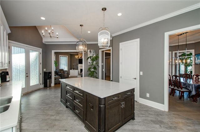 kitchen featuring french doors, dark brown cabinetry, a chandelier, hanging light fixtures, and ornamental molding