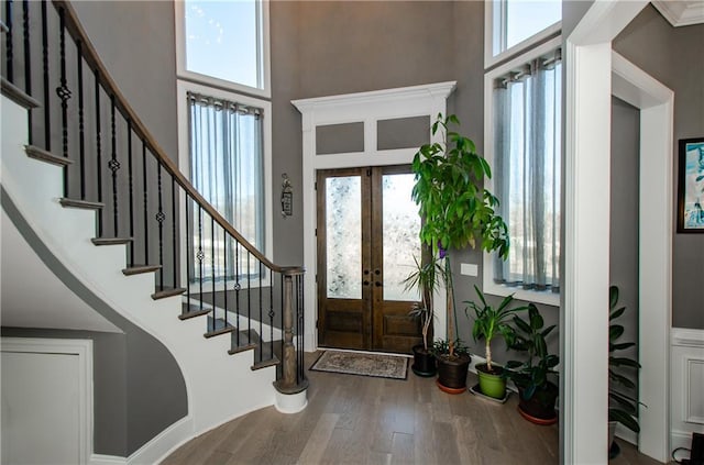 entryway featuring stairs, french doors, a high ceiling, and wood finished floors