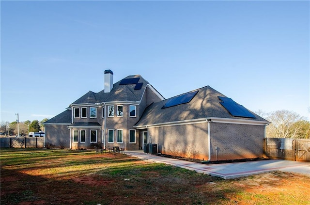 back of house featuring cooling unit, a yard, and solar panels