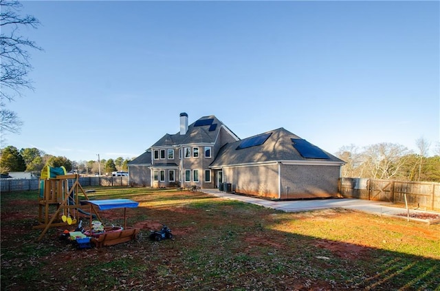 rear view of property featuring a lawn, a fenced backyard, cooling unit, and a playground