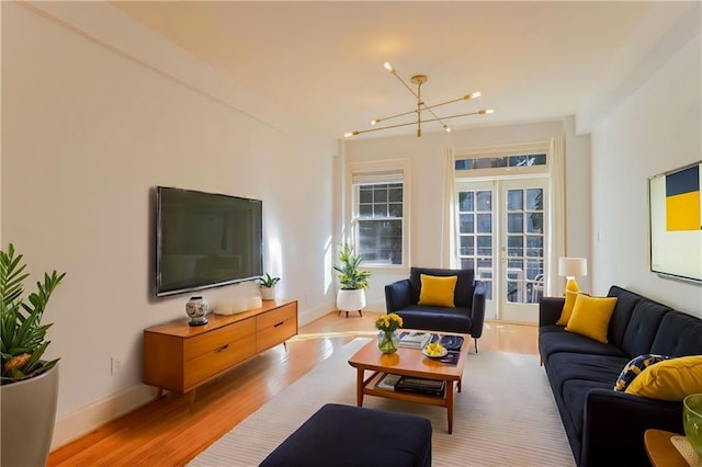 living room with french doors, an inviting chandelier, and light hardwood / wood-style floors