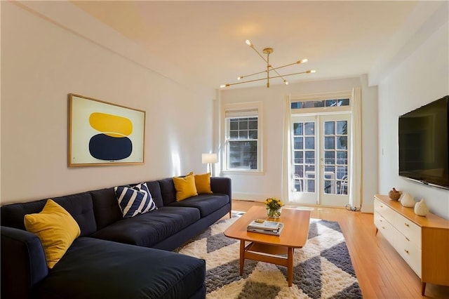 living room featuring french doors, a notable chandelier, and light wood finished floors