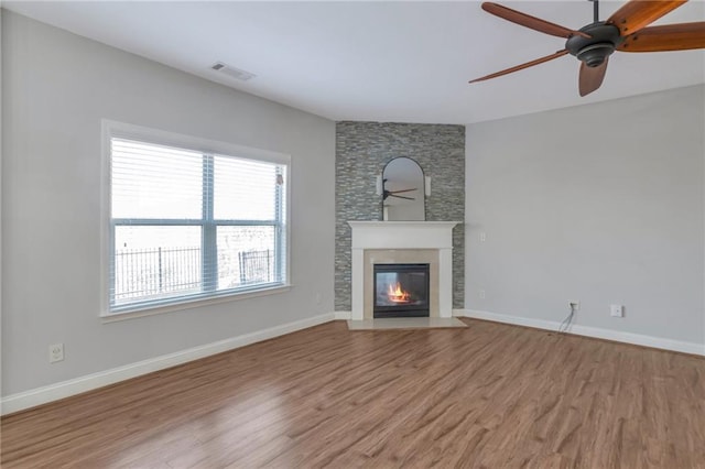 unfurnished living room featuring light hardwood / wood-style flooring, ceiling fan, and a large fireplace