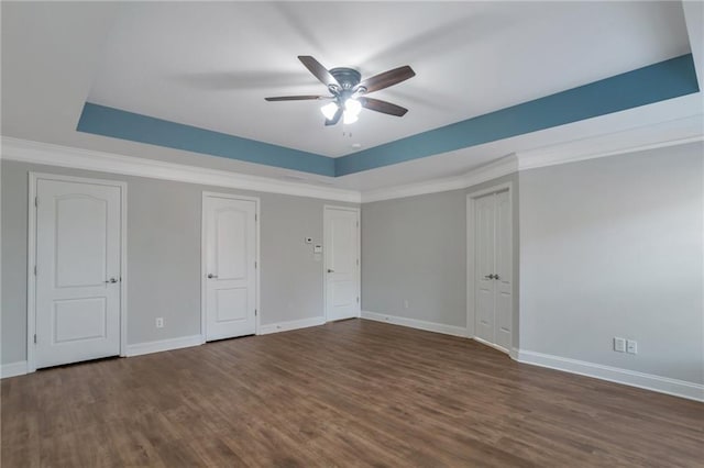 unfurnished bedroom with a tray ceiling, dark hardwood / wood-style floors, and ornamental molding