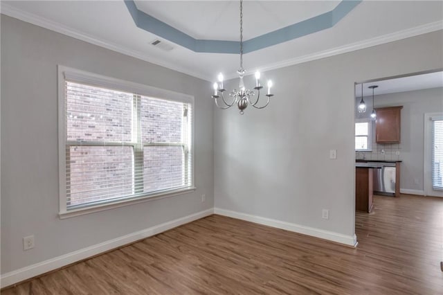 empty room featuring a raised ceiling, a chandelier, and dark hardwood / wood-style floors