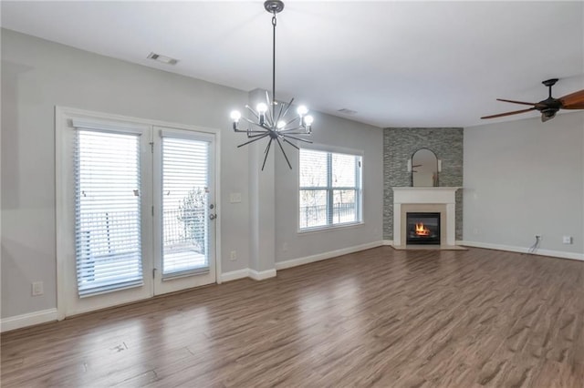 unfurnished living room with hardwood / wood-style floors, ceiling fan with notable chandelier, and a fireplace