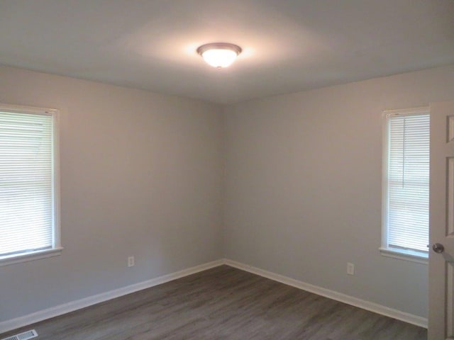 spare room with plenty of natural light and dark wood-type flooring