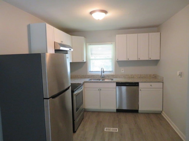 kitchen with white cabinetry, light hardwood / wood-style floors, light stone countertops, and appliances with stainless steel finishes