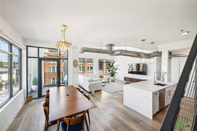 kitchen featuring white cabinetry, sink, pendant lighting, and light wood-type flooring