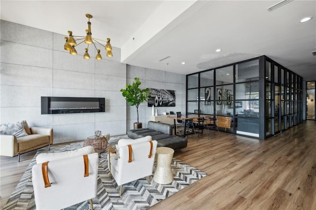 living room with a wall of windows, tile walls, wood-type flooring, and a notable chandelier