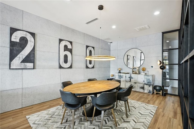 dining area featuring tile walls and light wood-type flooring